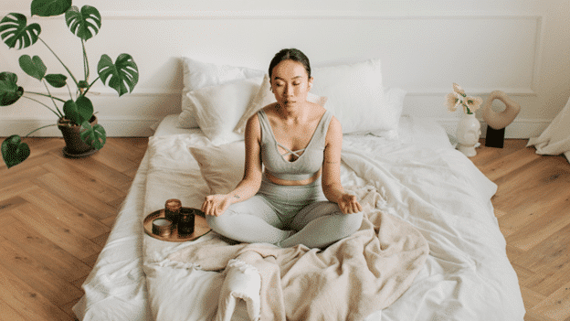 a woman sitting on a bed while meditating